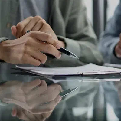 A hand with a pen working with documents at the desk, close-up.
