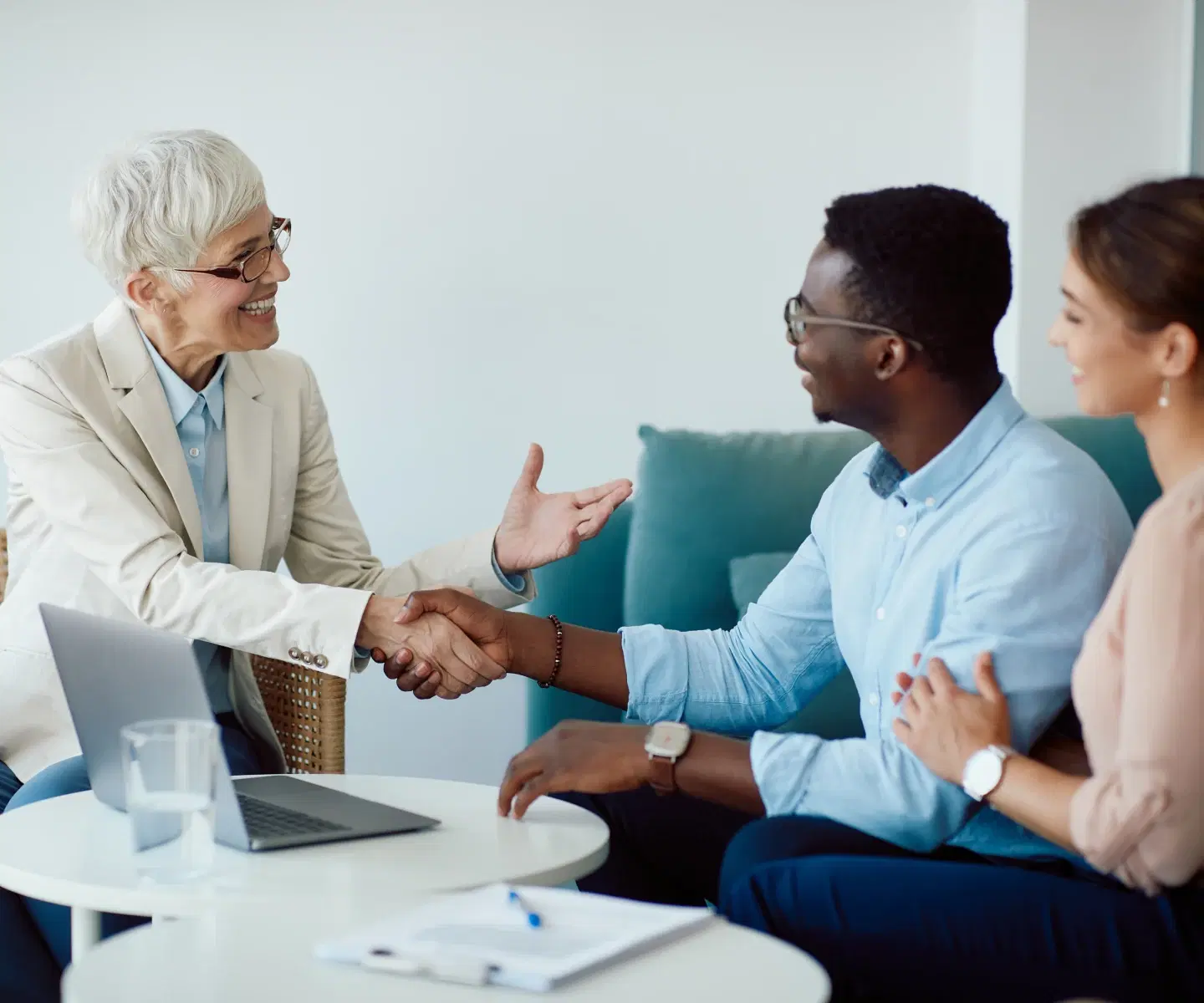 A financial advisor shaking hands with a couple.
