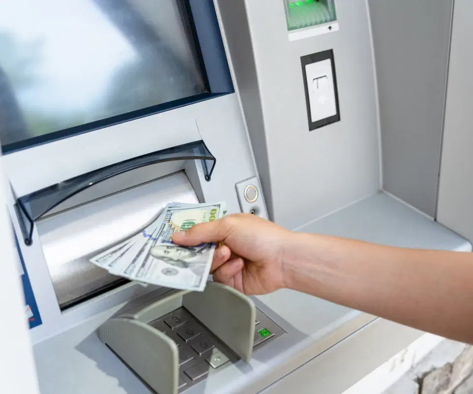 A woman withdrawing a money bill, holding an American hundred-dollar cash.