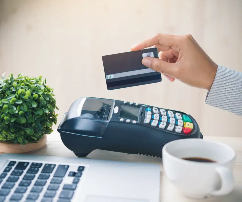 Close-up of a hand holding a credit card and paying at the POS terminal.