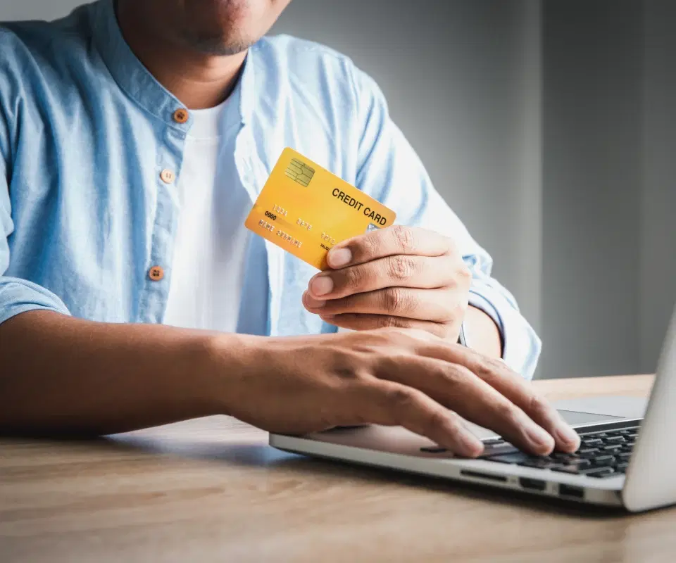 Hands holding a credit card and using a laptop